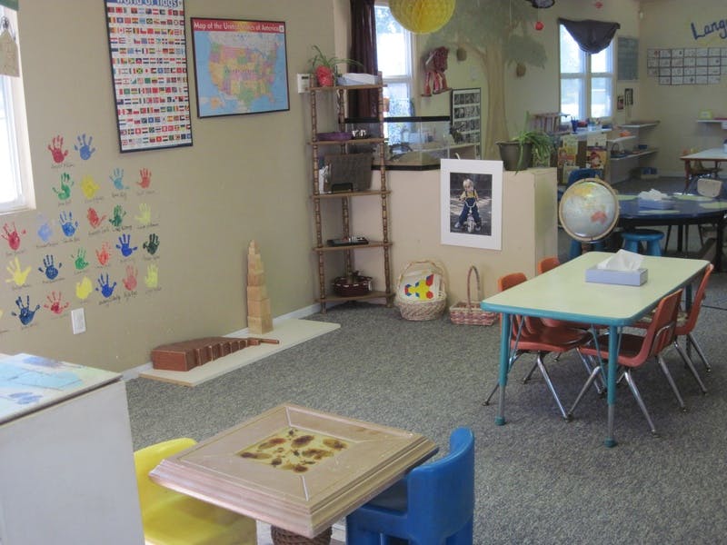 Classroom with small tables and chairs, handprint art on wall