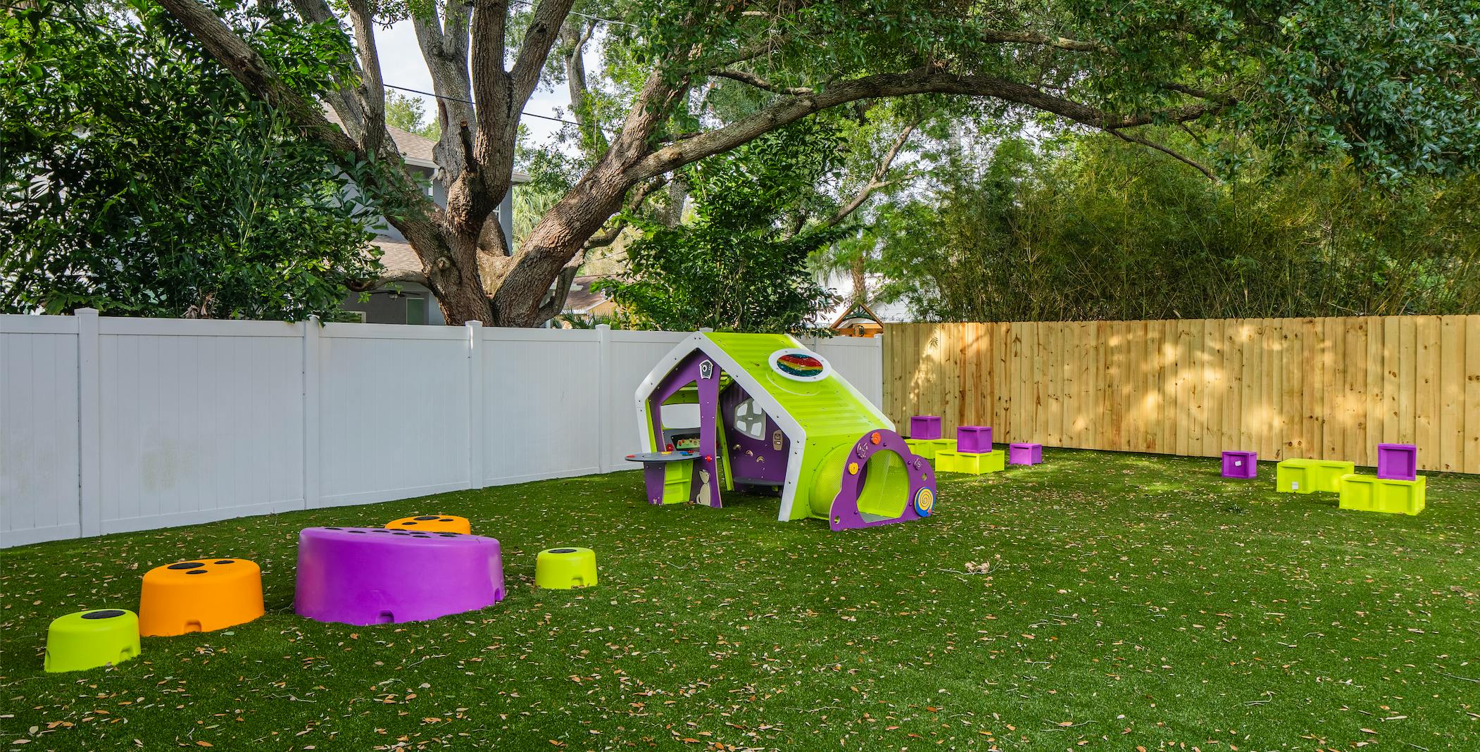 Playground with green and purple playhouse with tunnel and various colorful seating