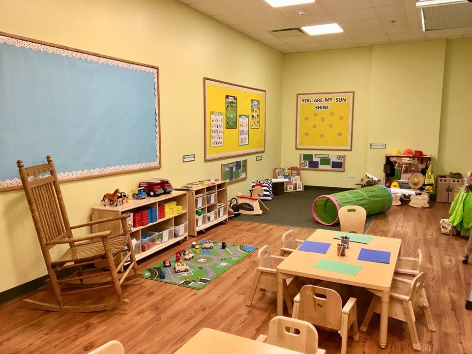 Classroom with small tables and chairs, toys, and bulletin boards