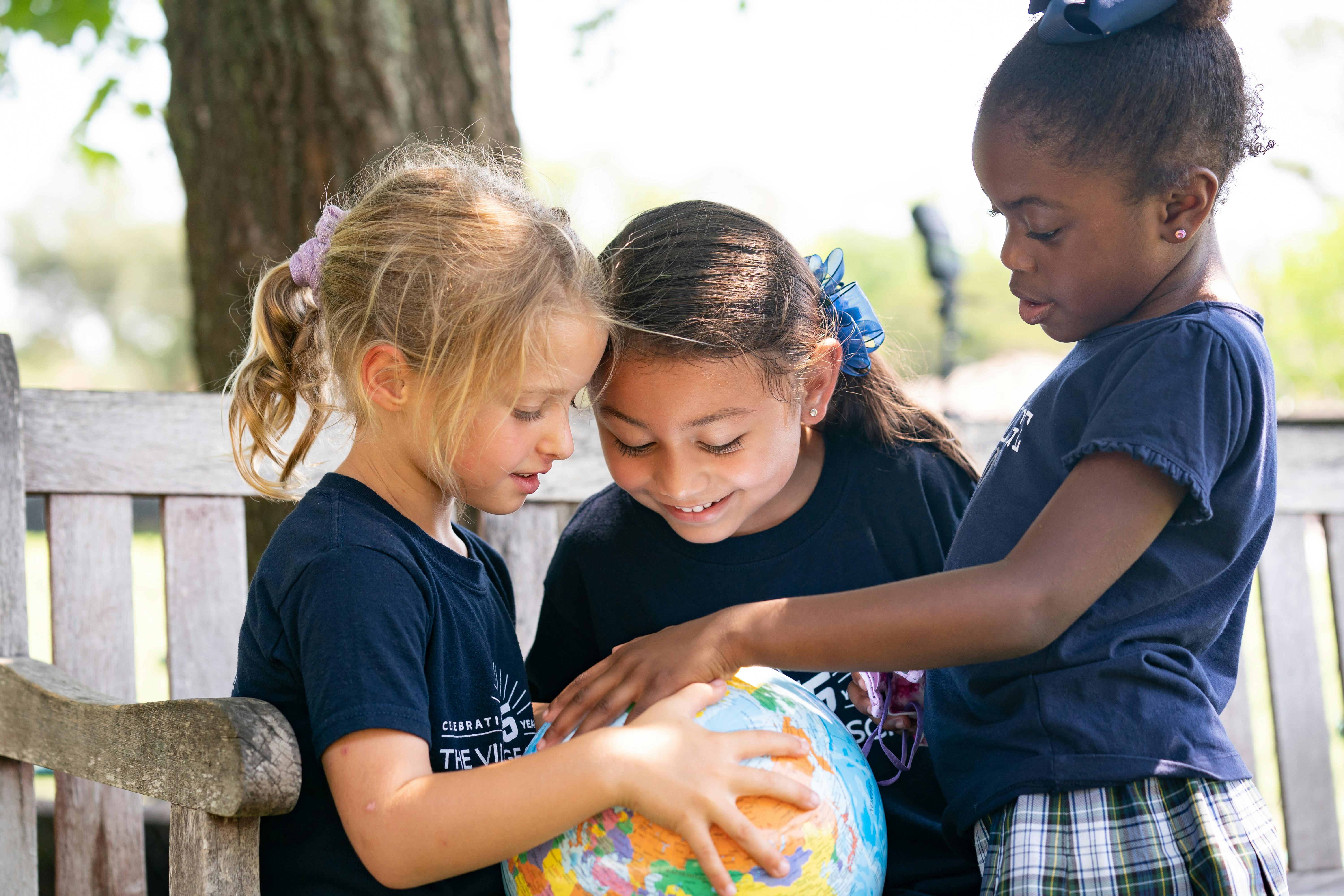 Three children looking at a globe
