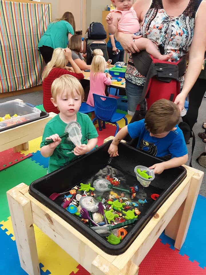 Two children playing with toys in a water table