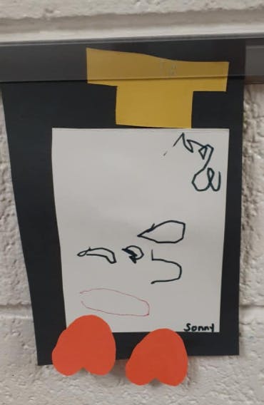 Child's drawing of a face with a signature below it