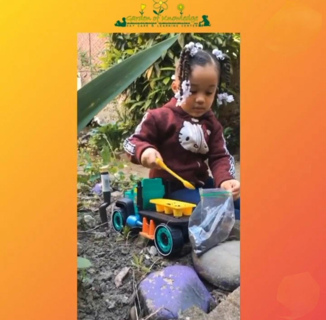 Child playing with a toy truck in a garden