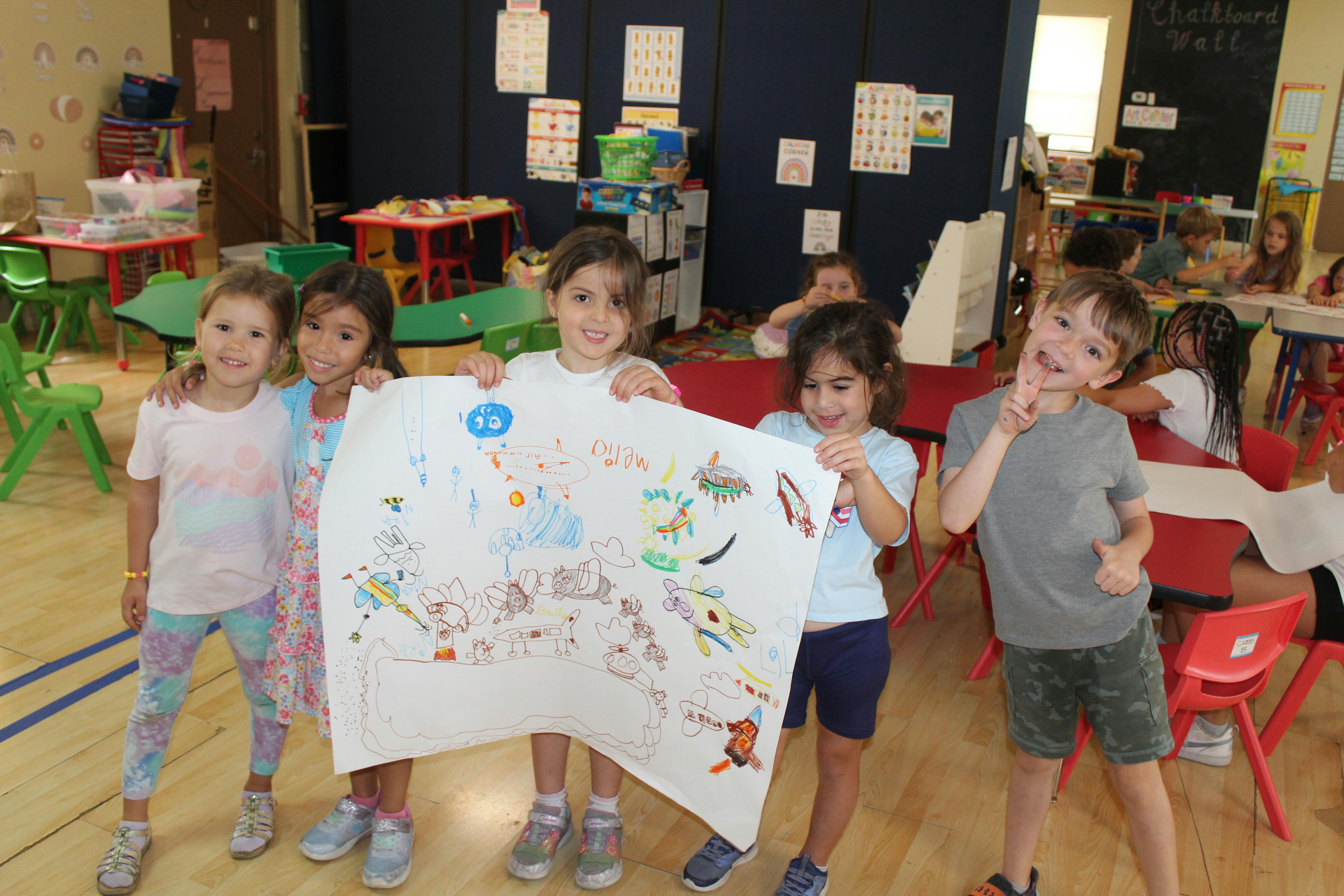 Children holding up a large drawing in a classroom