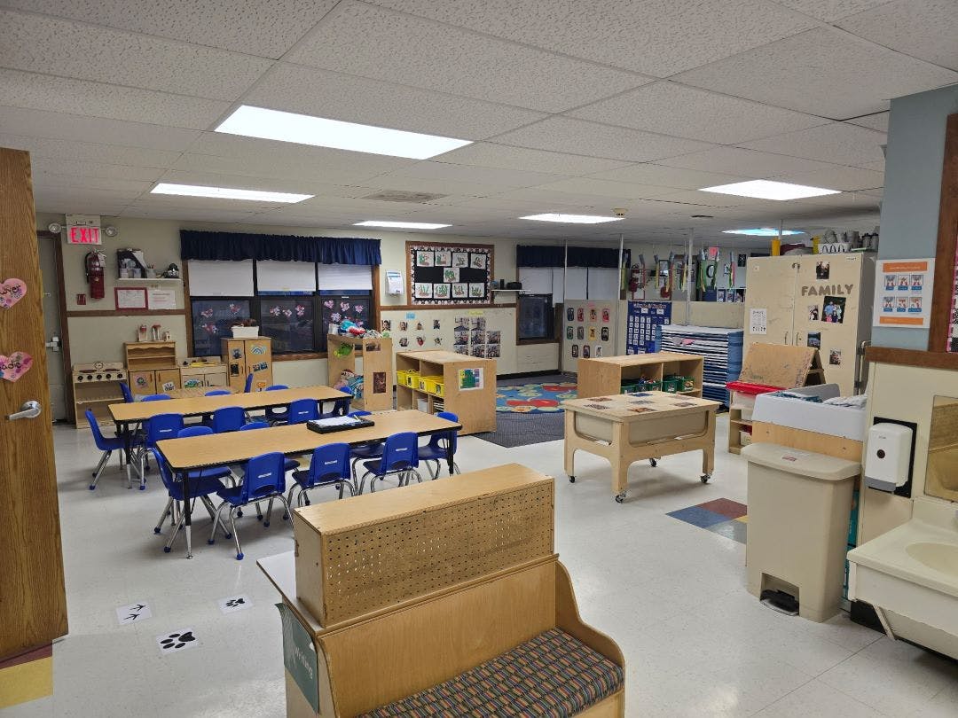 Classroom with small tables and chairs, play kitchen, and activity centers