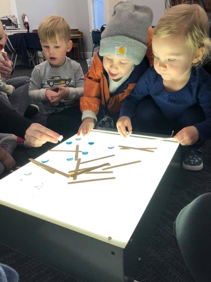 Children playing with objects on a light table