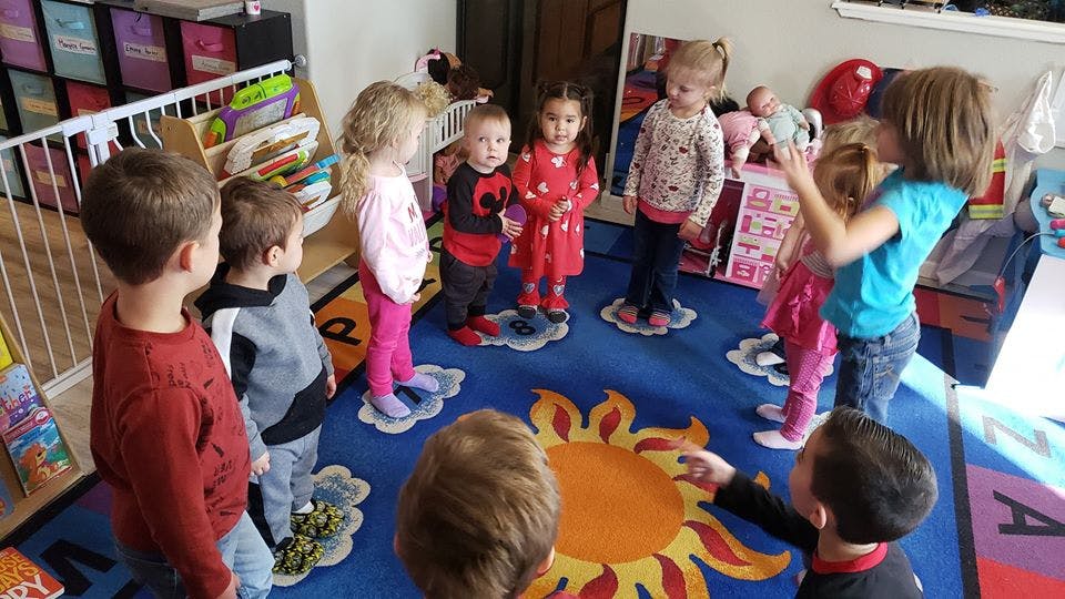 Children standing on cloud shapes on a sun rug
