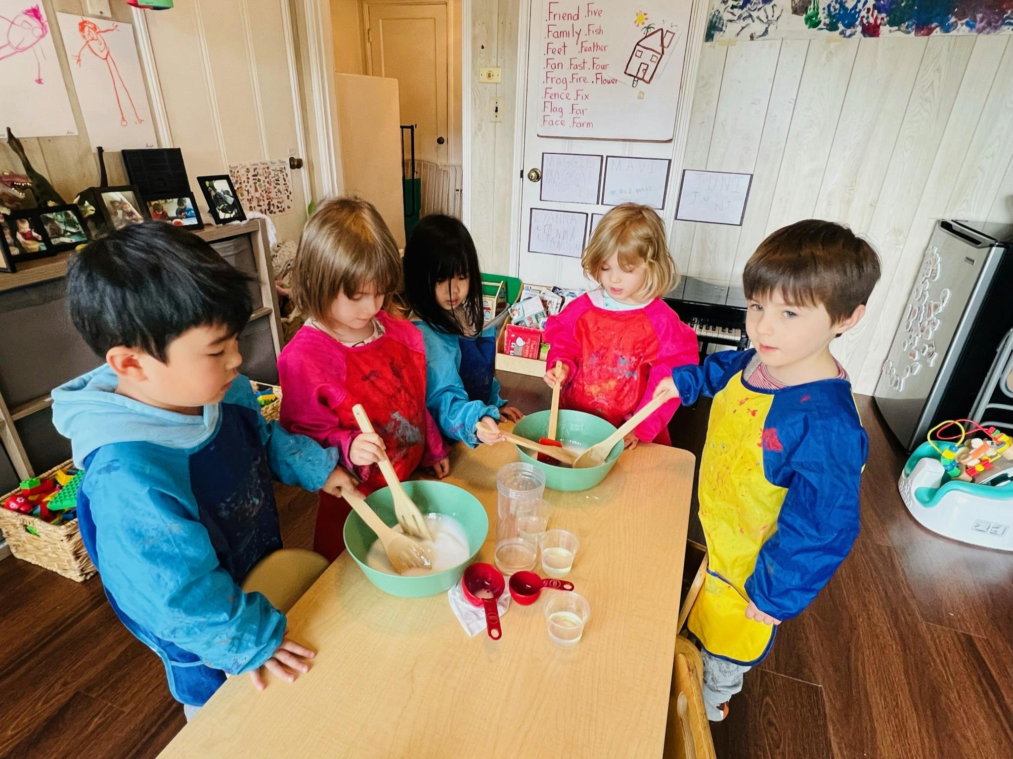 Children mixing ingredients in bowls at a table
