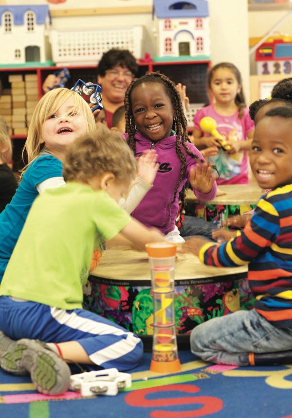 Children playing drums and other instruments in a classroom