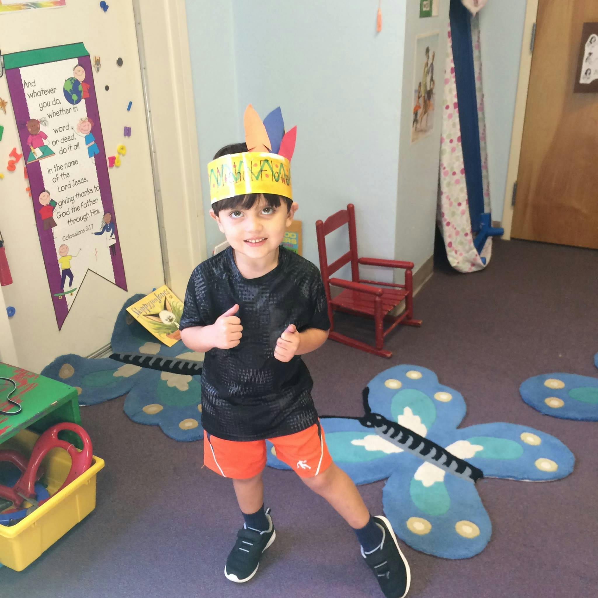 Child wearing a feather headband in a classroom