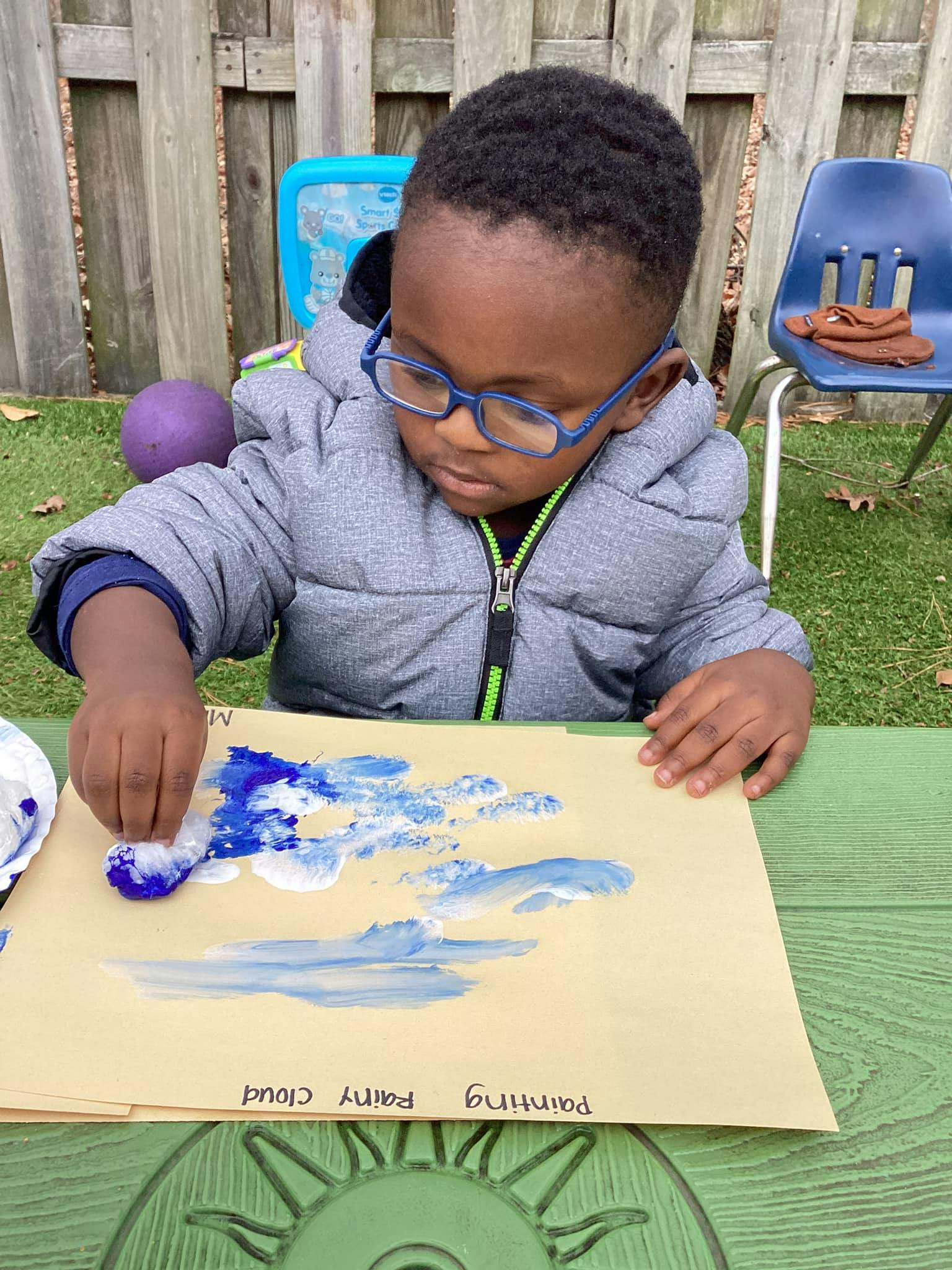 Child painting with blue and white paint on paper