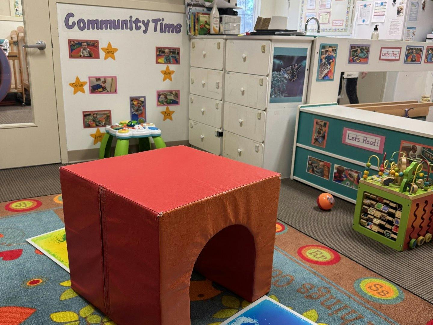 a children's play area with a red climbing block on a colorful rug