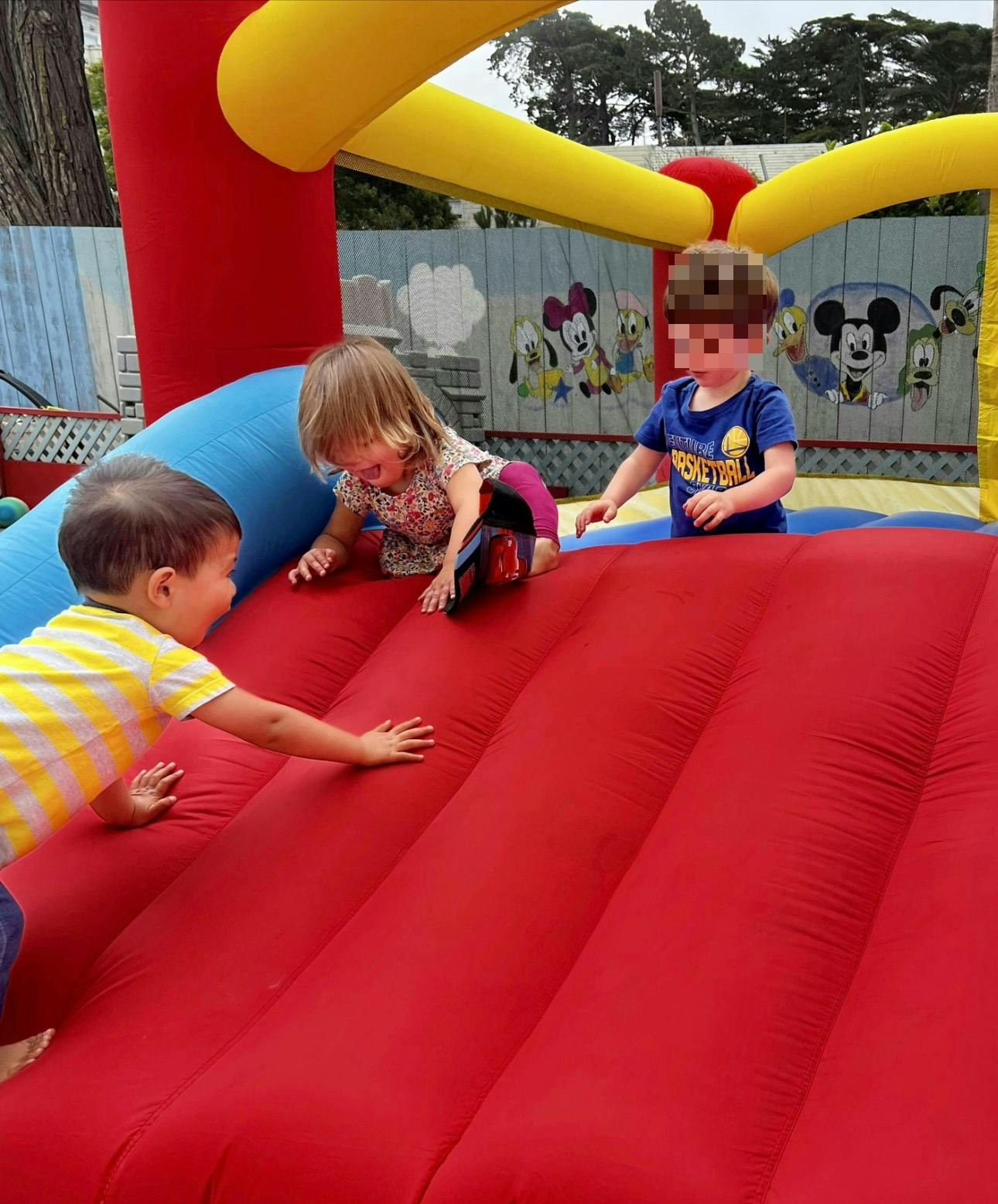Three children playing on an inflatable bounce house