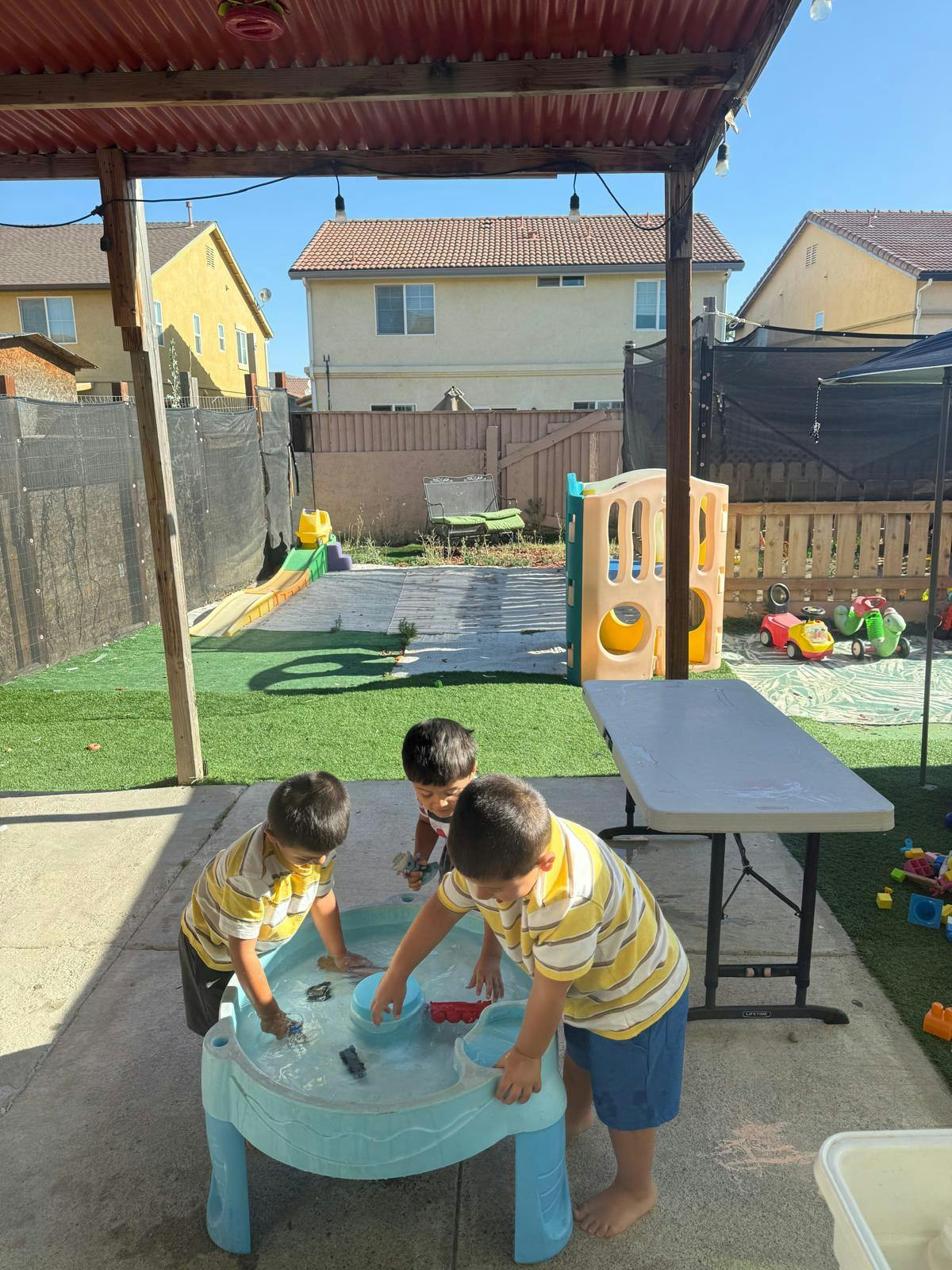 Three children playing with a water table outdoors