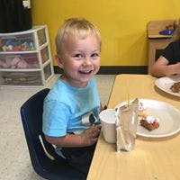 Child sitting at a table with a plate and cup