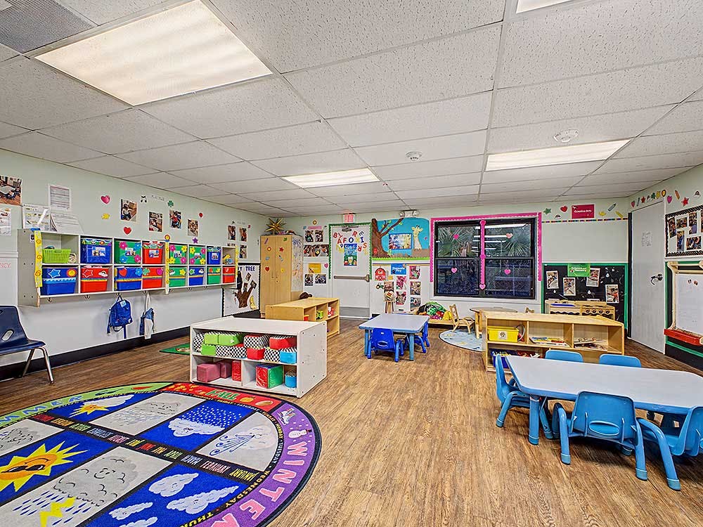 Colorful and organized classroom with small tables, chairs, and learning decorations