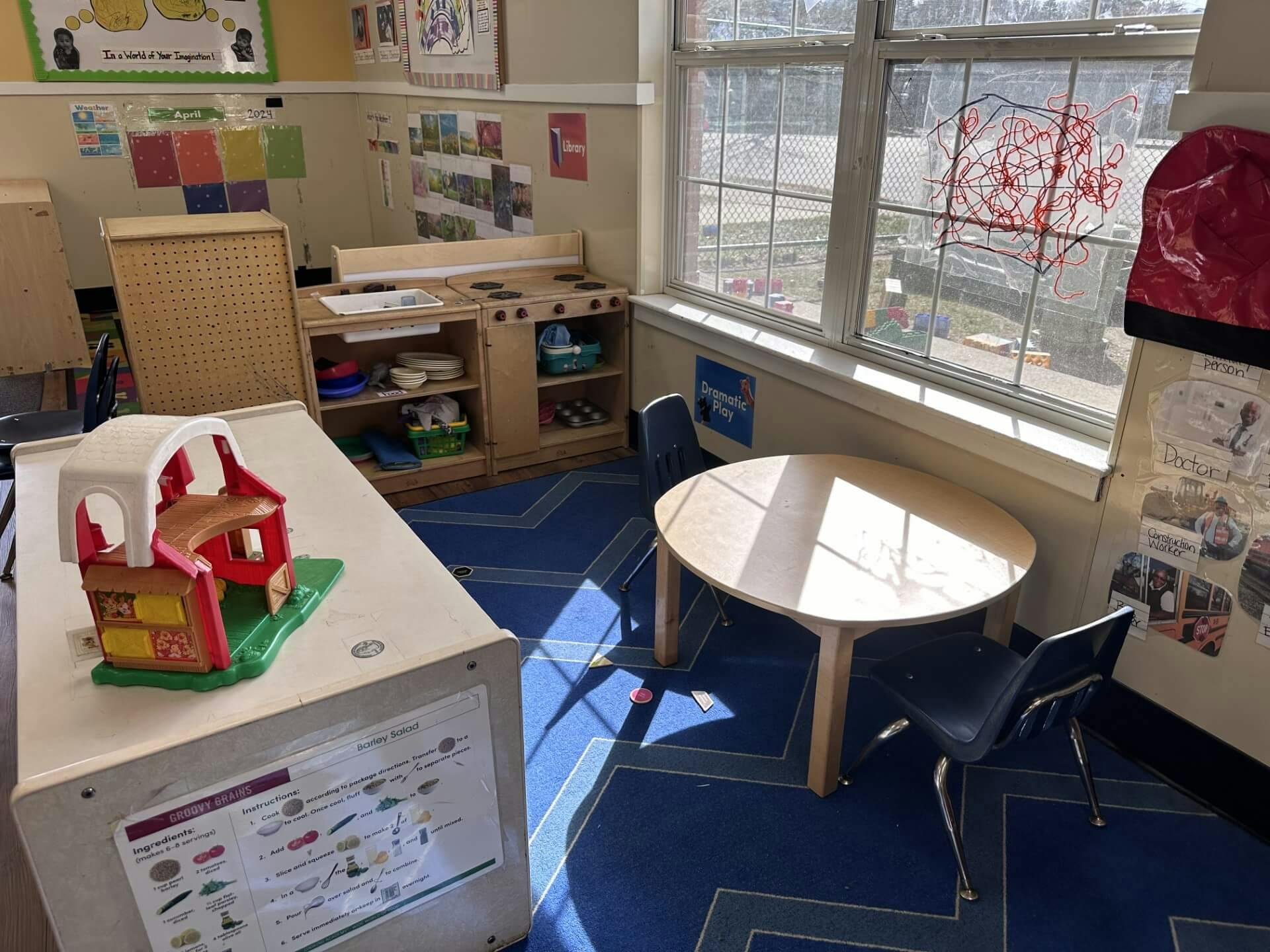 Classroom corner with play kitchen, small table and chairs, toy house