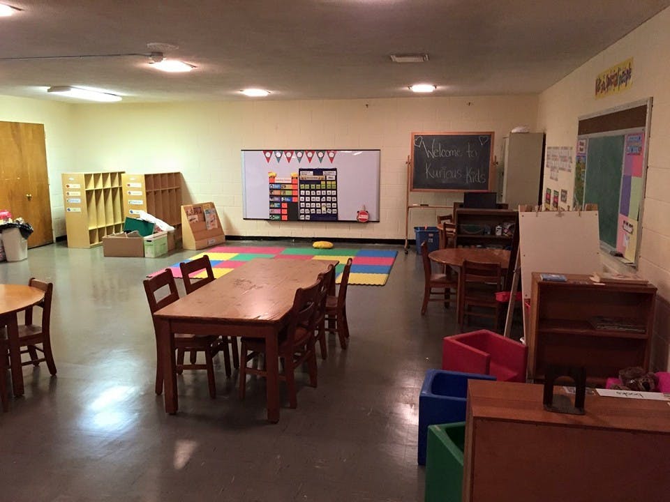 Classroom with tables, chairs, and a colorful play mat