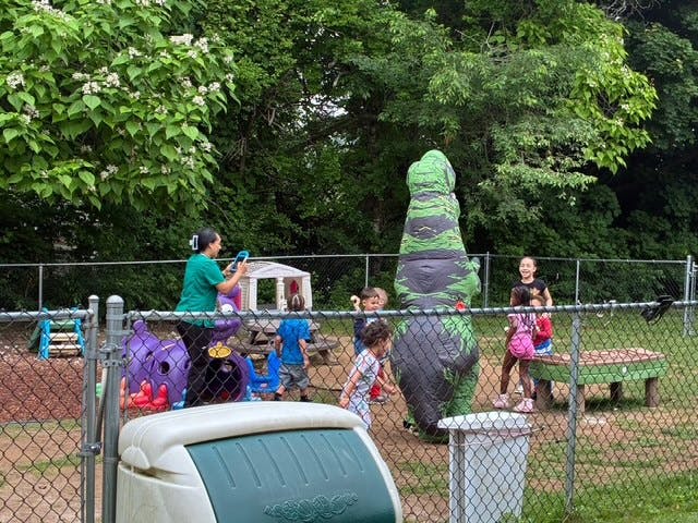A person in a dinosaur costume playing with children on a playground