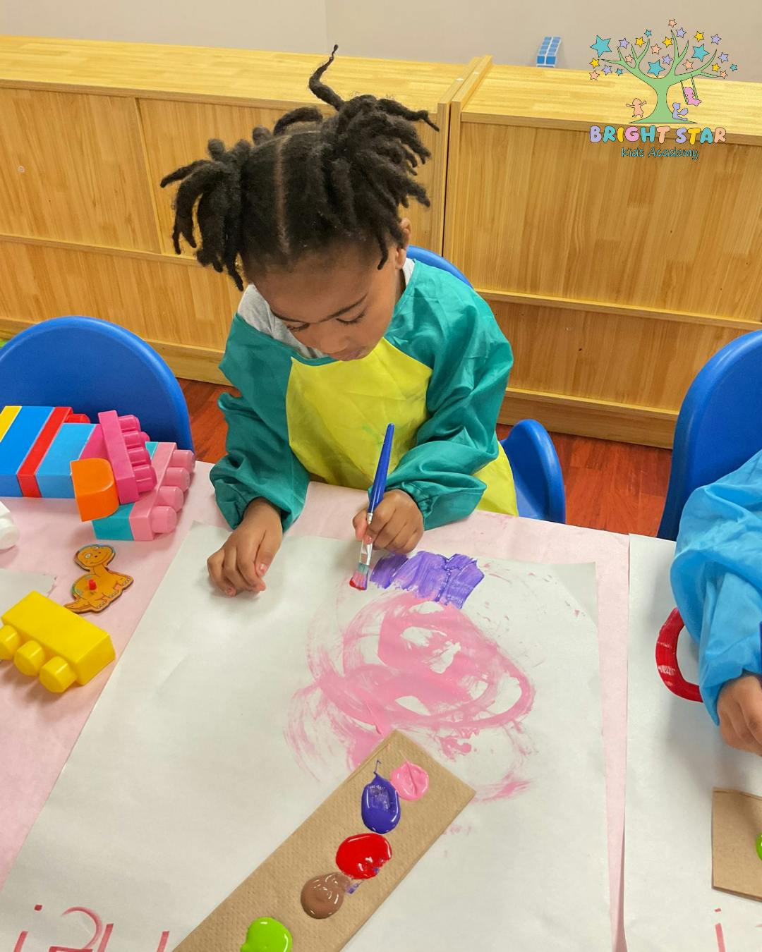 Child painting on paper with a paintbrush
