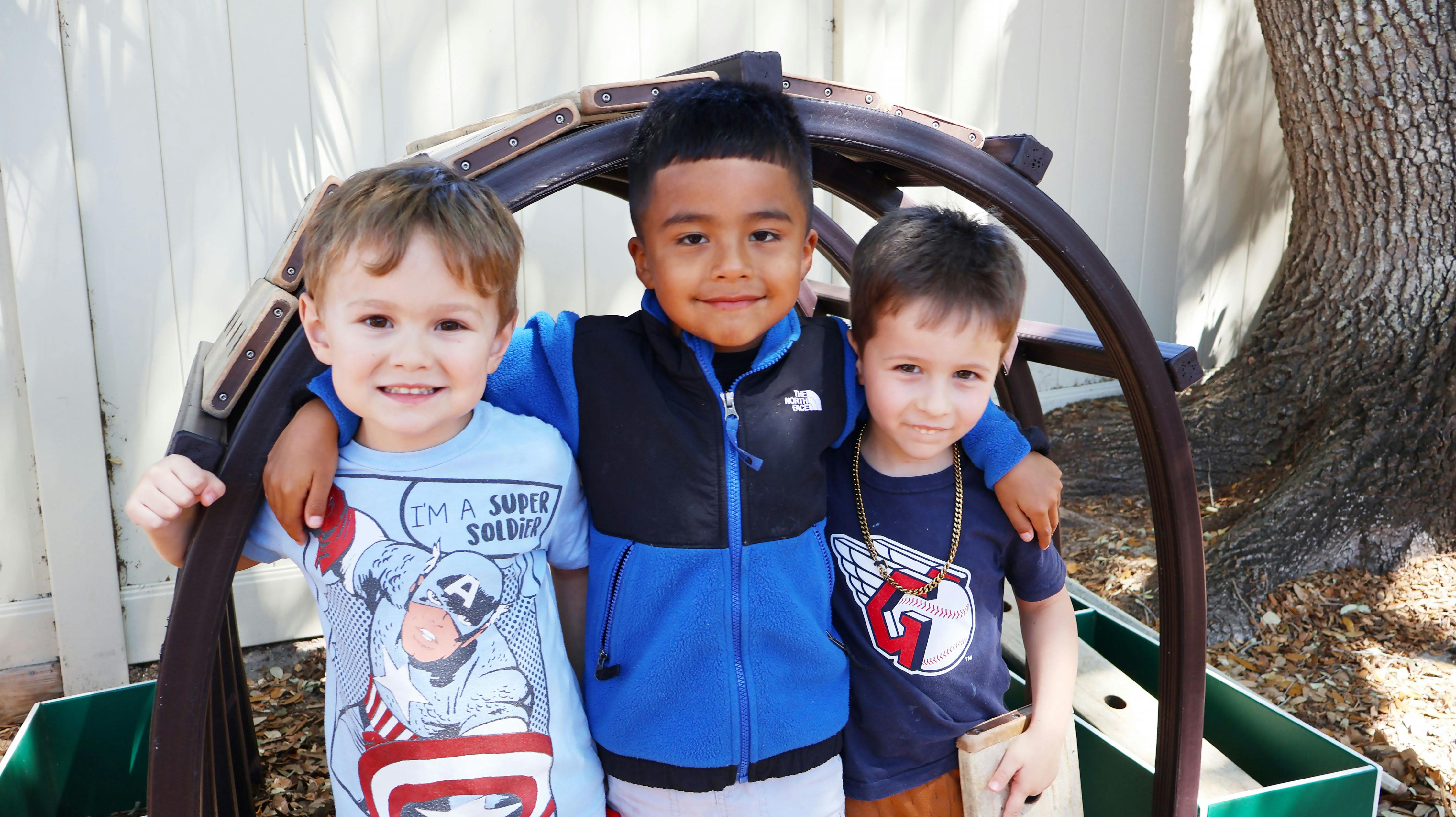 Three children standing together, two with arms around each other