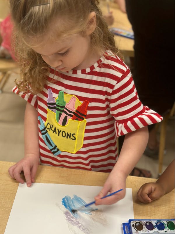 Child painting on paper with a paintbrush