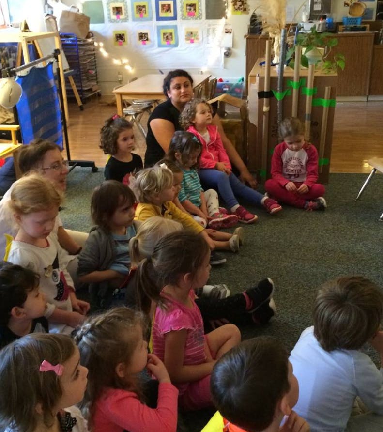 Adult and children sitting on the floor in a classroom