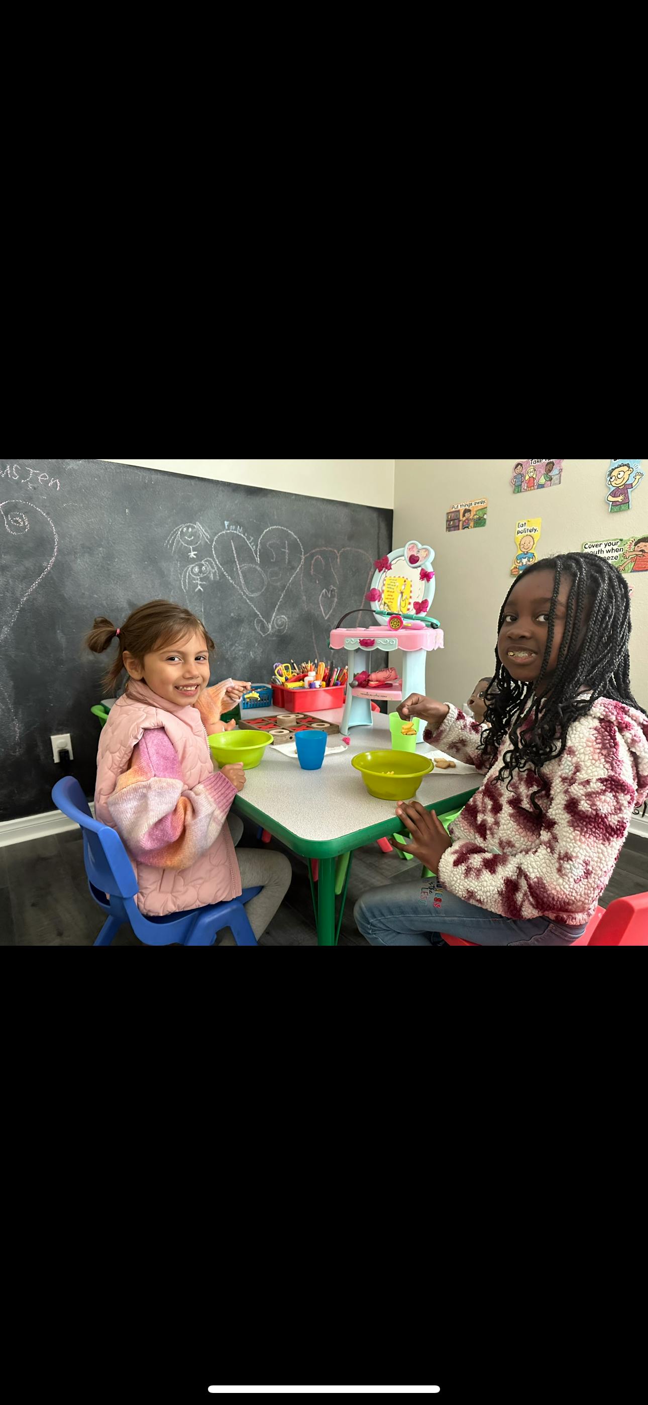 Two children sitting at a table with bowls and cups