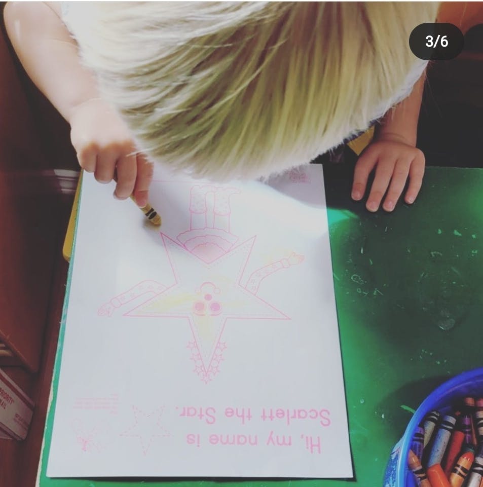 Child drawing on paper with a crayon