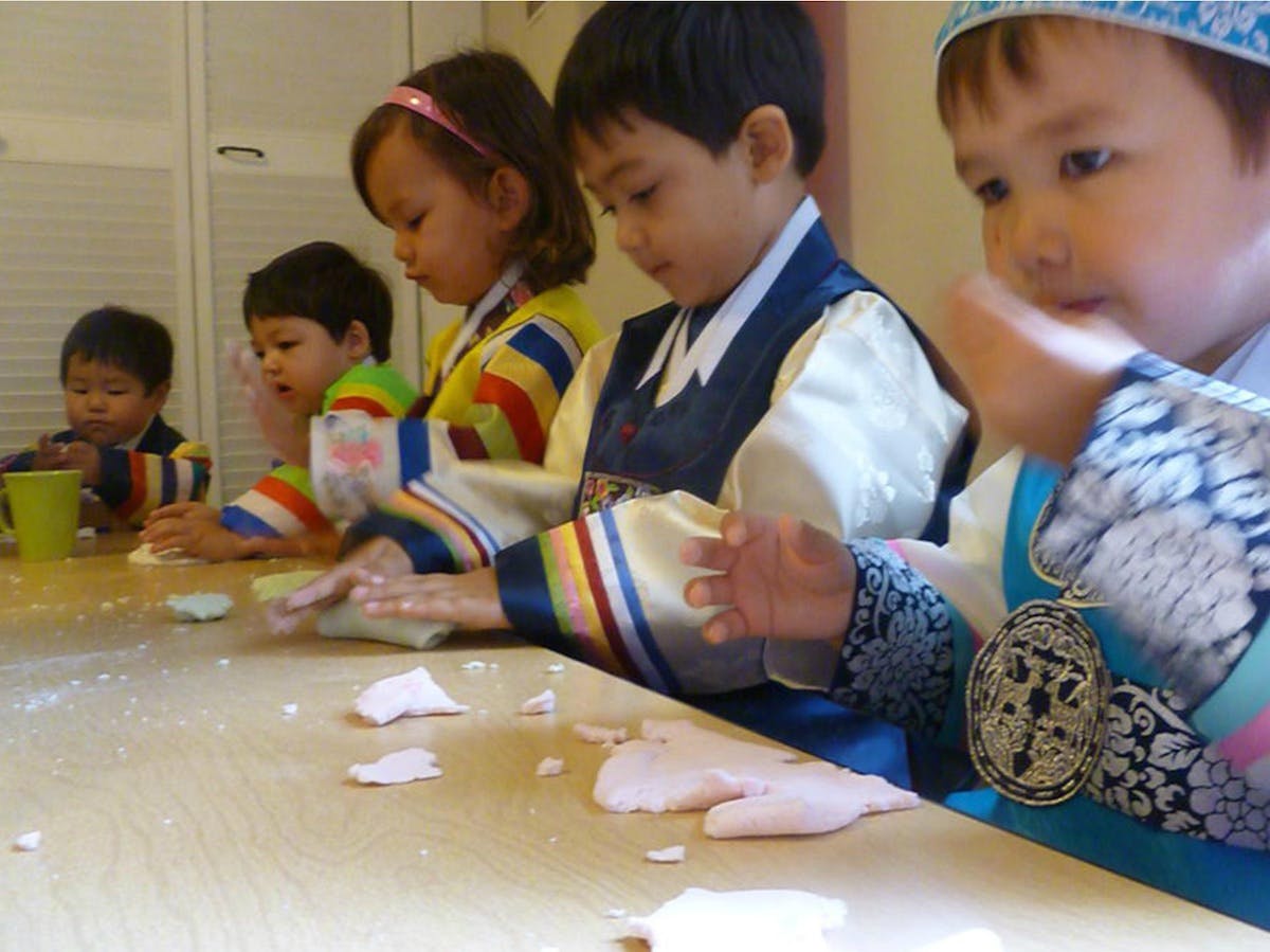 Four children at a table playing with dough