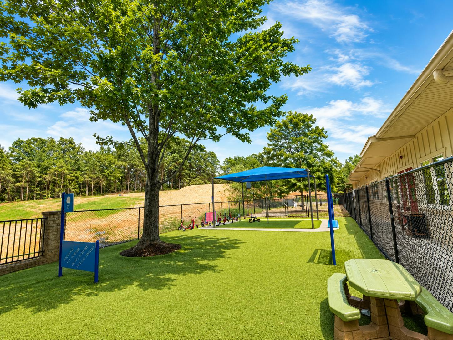 Playground area with a blue shade canopy and children's ride-on toys