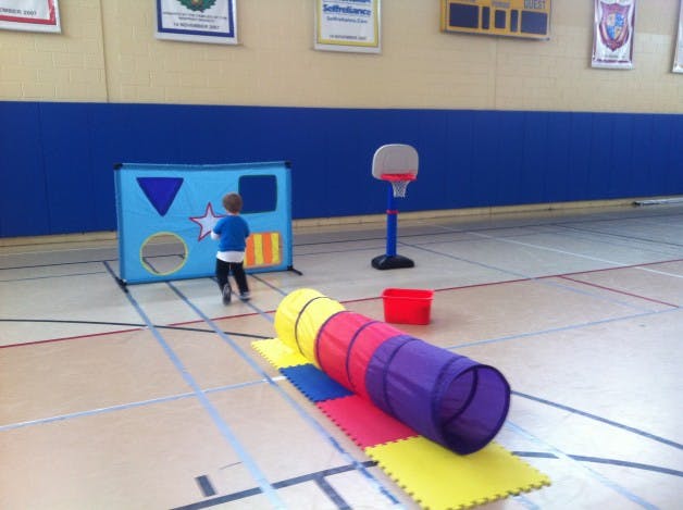 Child playing with a shape sorter toy in a gym