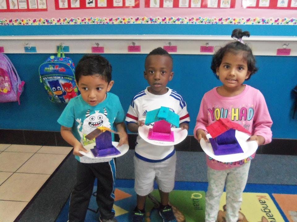 Three children holding paper plates with colorful paper crafts