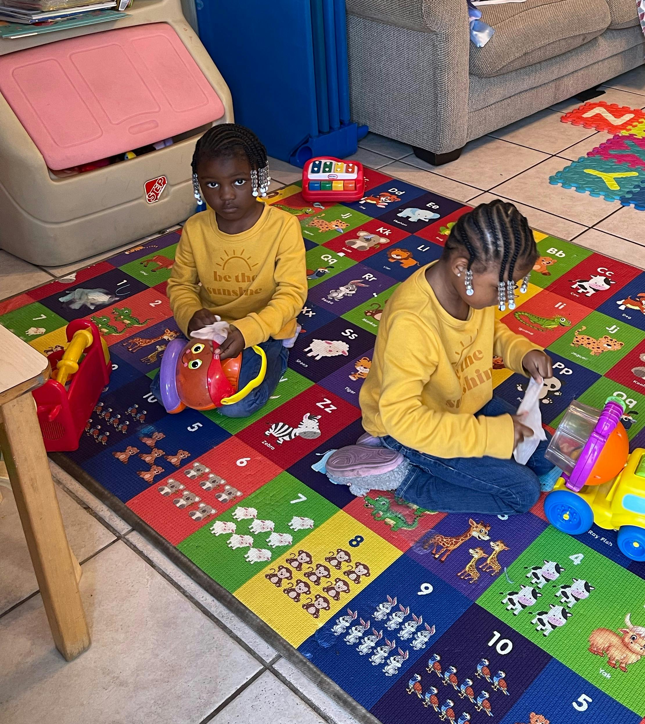 Two children playing on a colorful number and animal rug