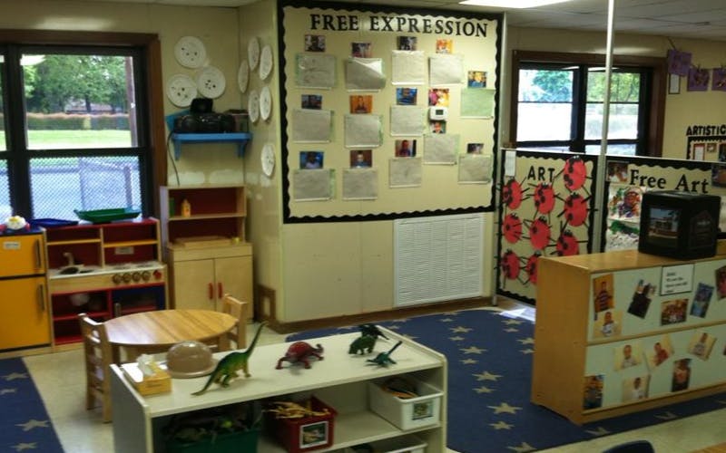 Classroom with play kitchen, small table and chairs, and art displays