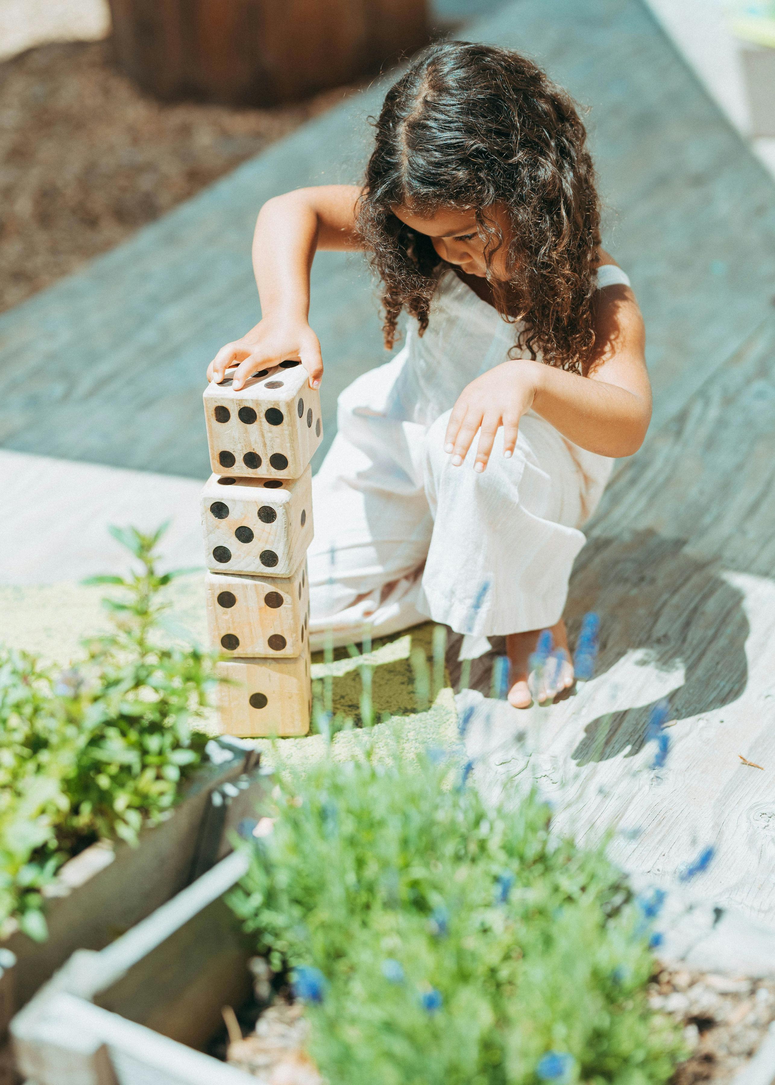 Child stacking large wooden dice outdoors