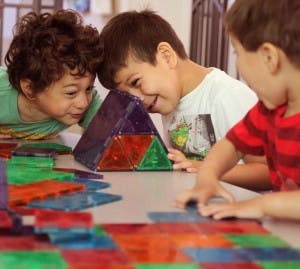 Three children playing with colorful magnetic tiles