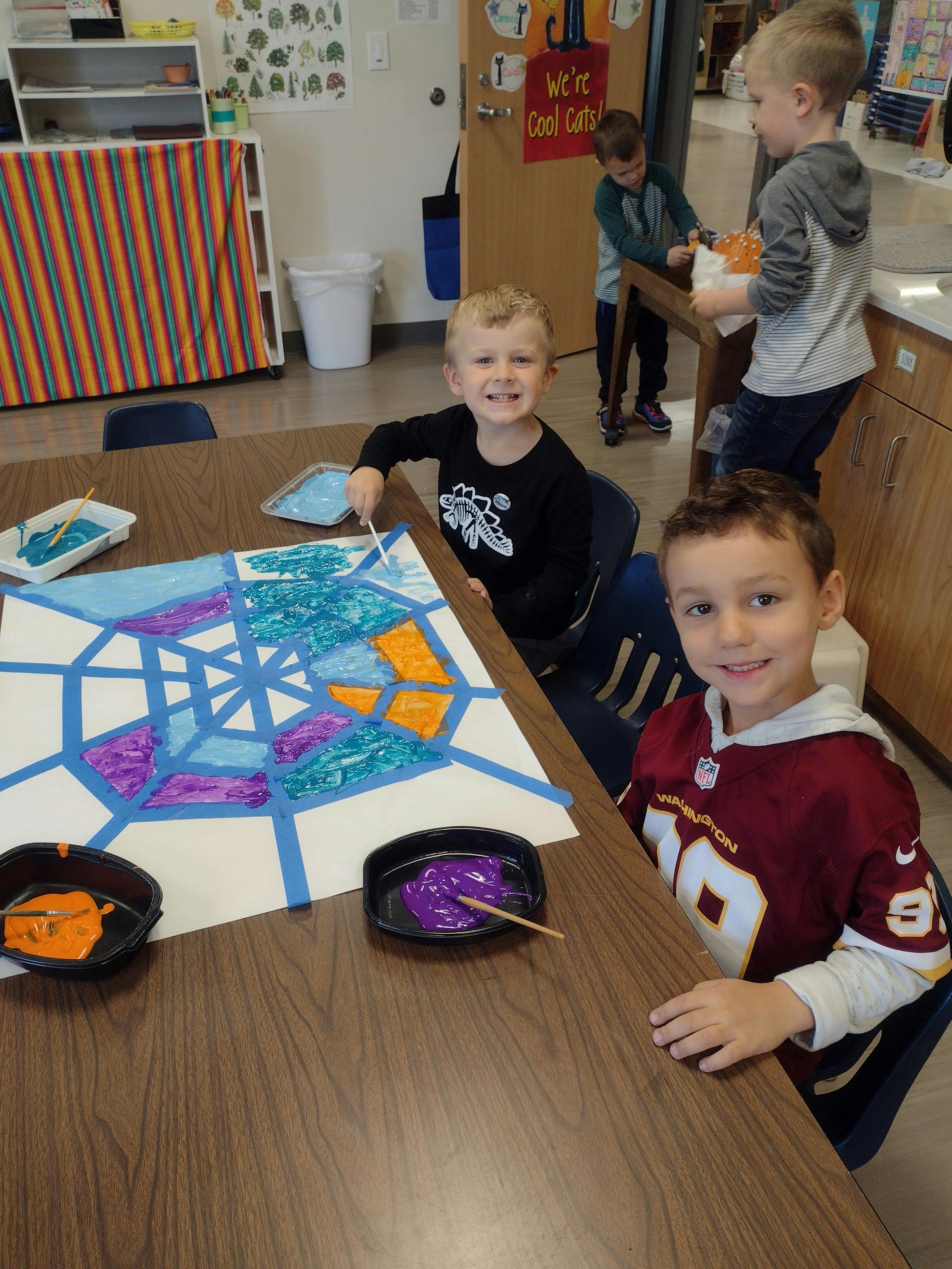 Two children painting at a table in a classroom