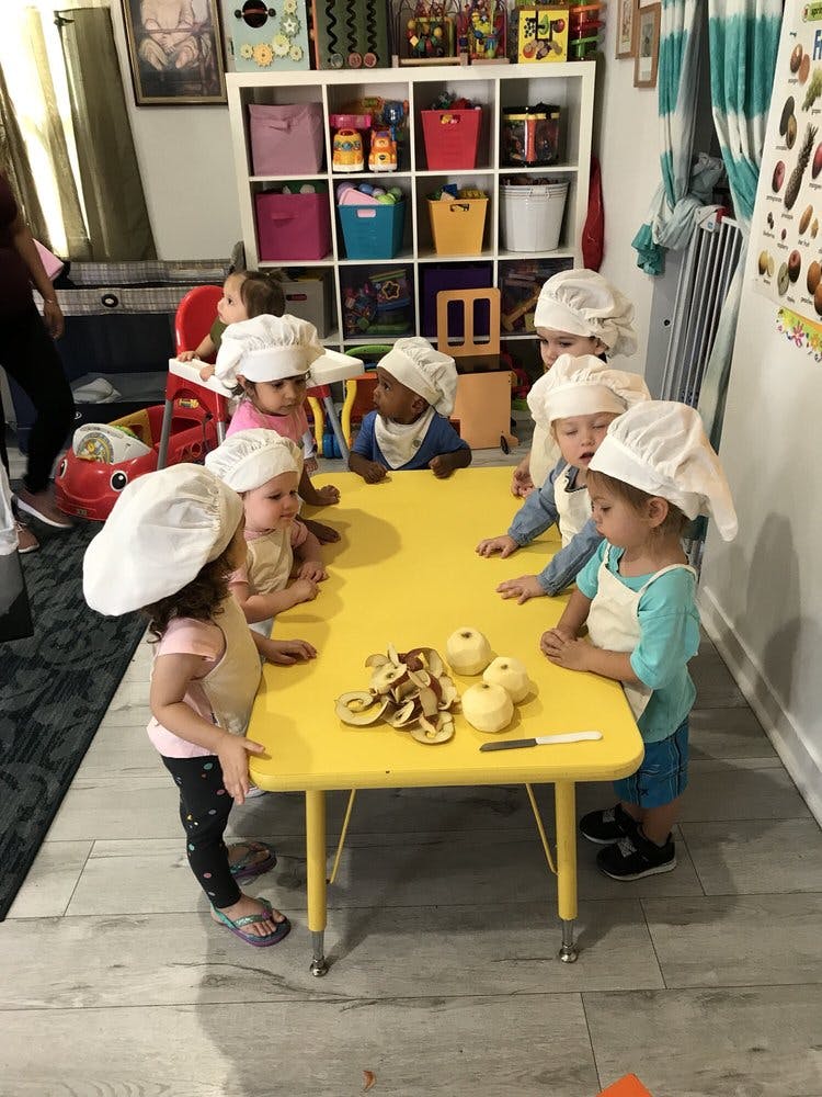 Children in chef hats and aprons around a table with apples and apple peels