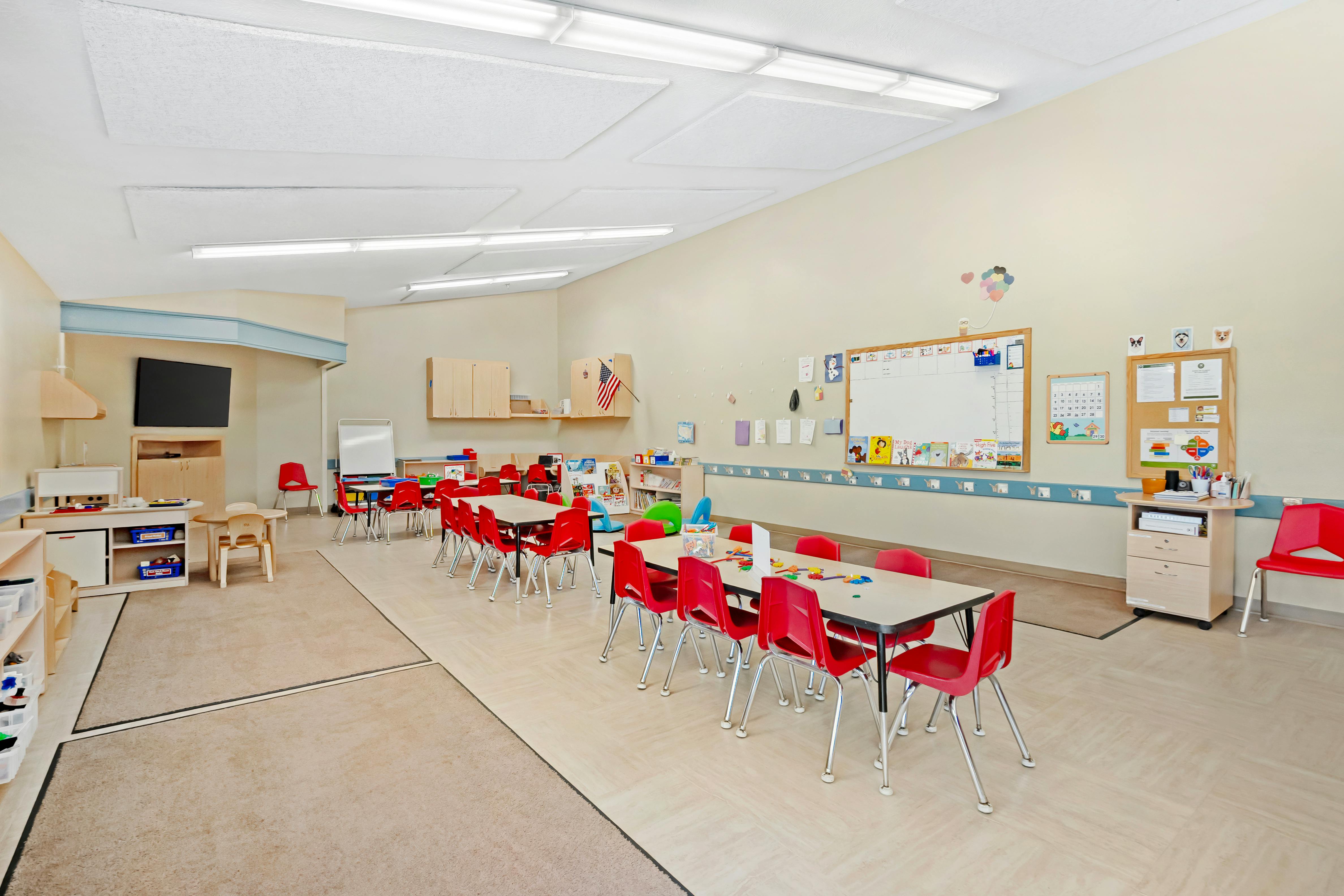 Classroom with multiple tables and red chairs for children