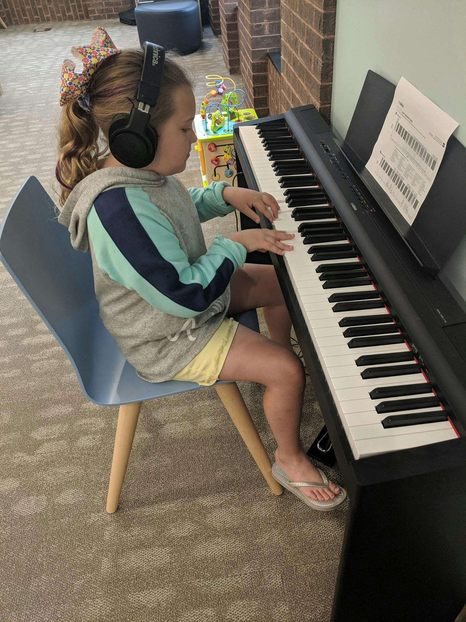 Child wearing headphones playing a digital piano