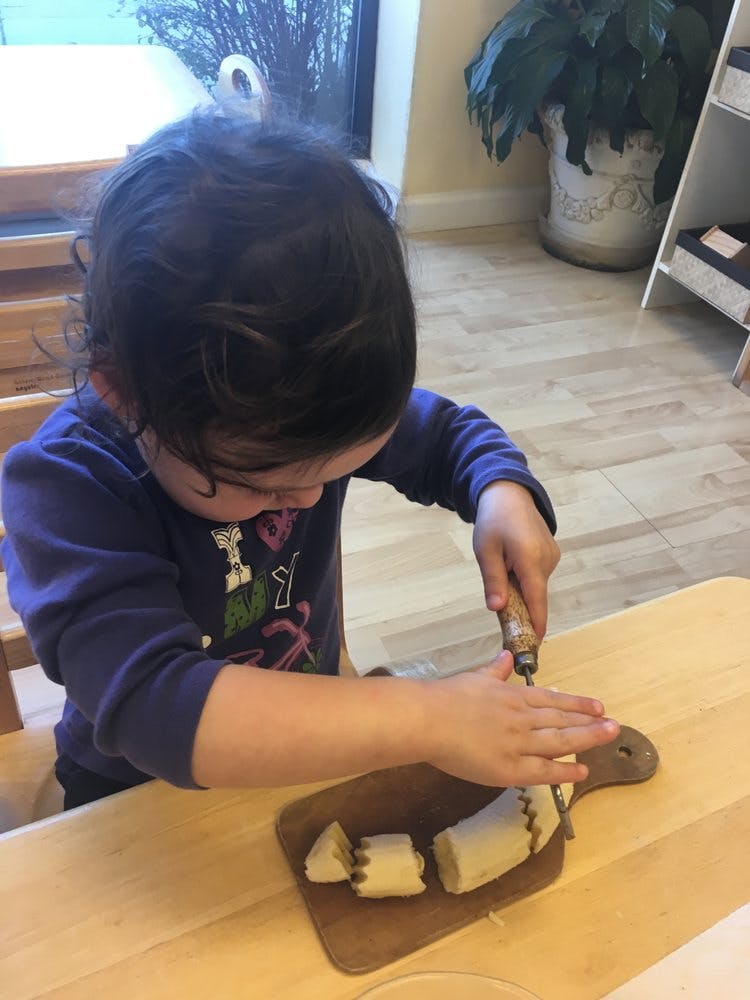 Child cutting a banana on a small cutting board