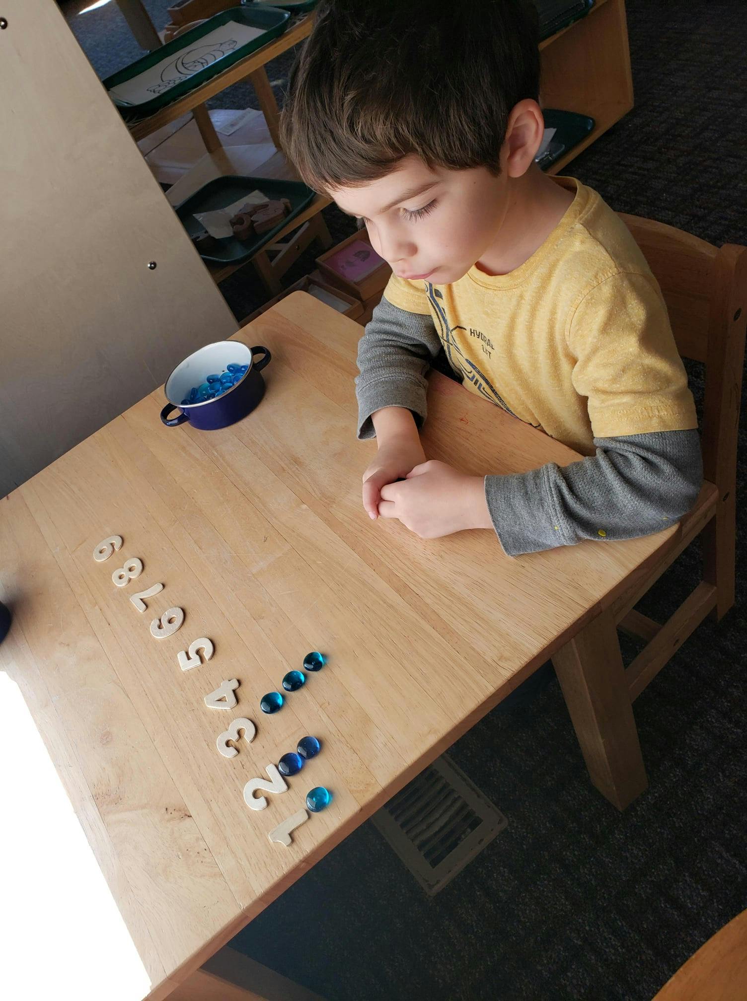 Child at a table with numbers and blue glass beads