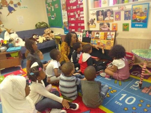 Adult person reading to a group of children in a classroom