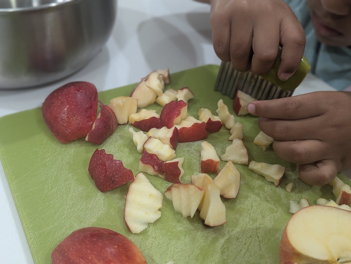 Person cutting apples on a green cutting board