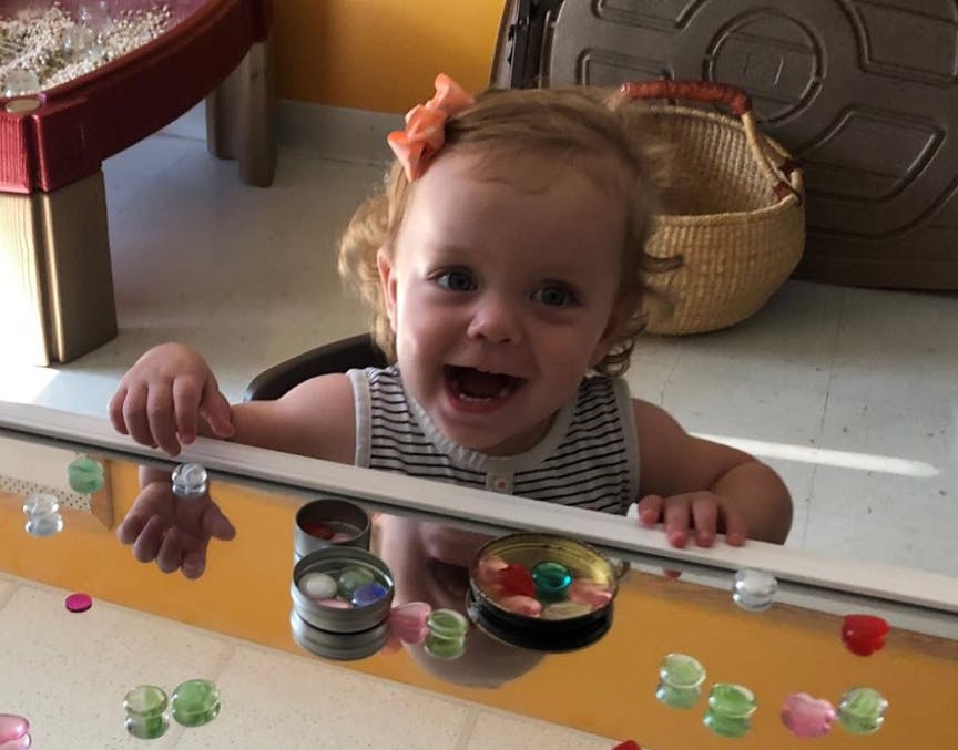 Child looking over a reflective surface with colorful objects
