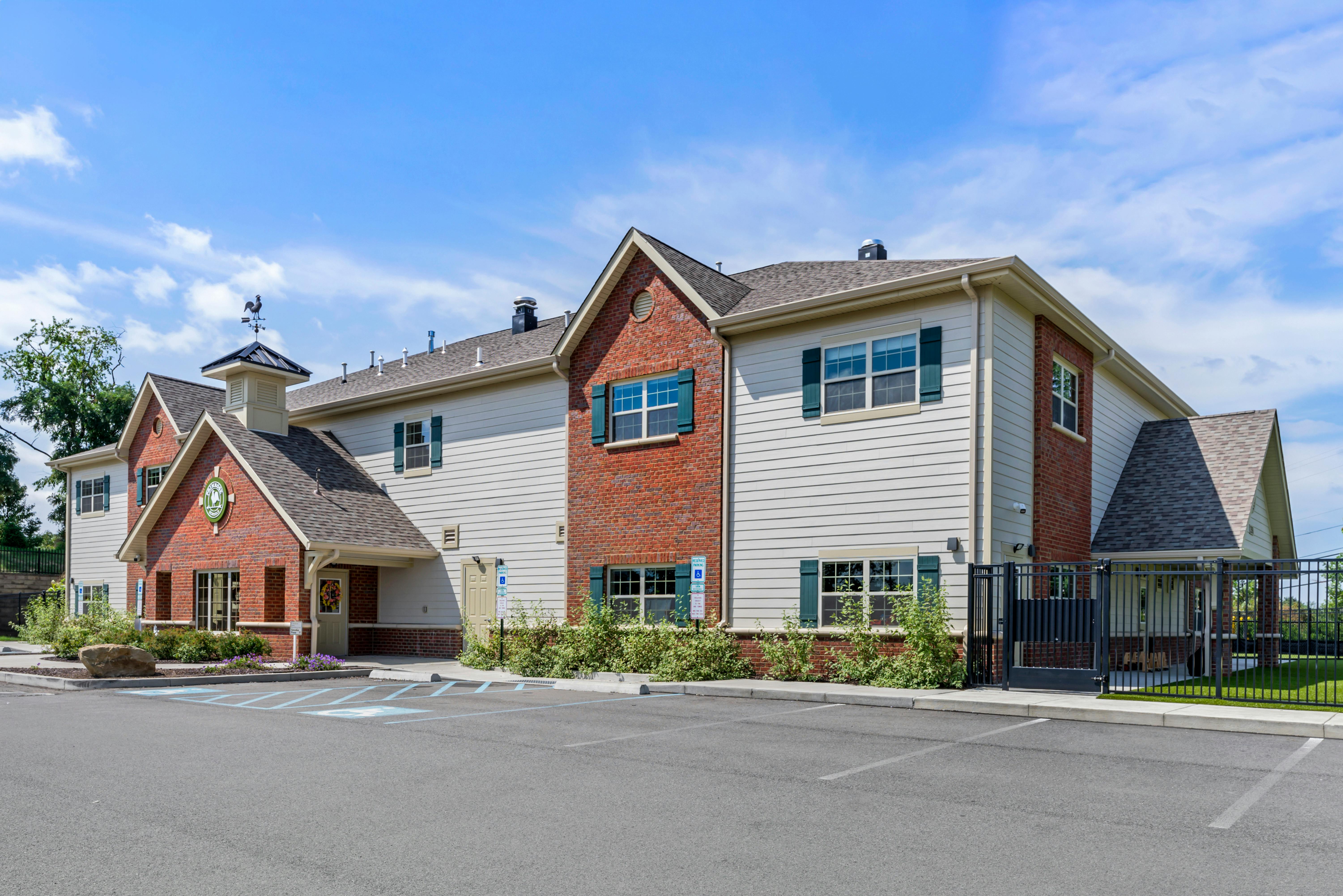 A beige building with brick accents and teal window shutters