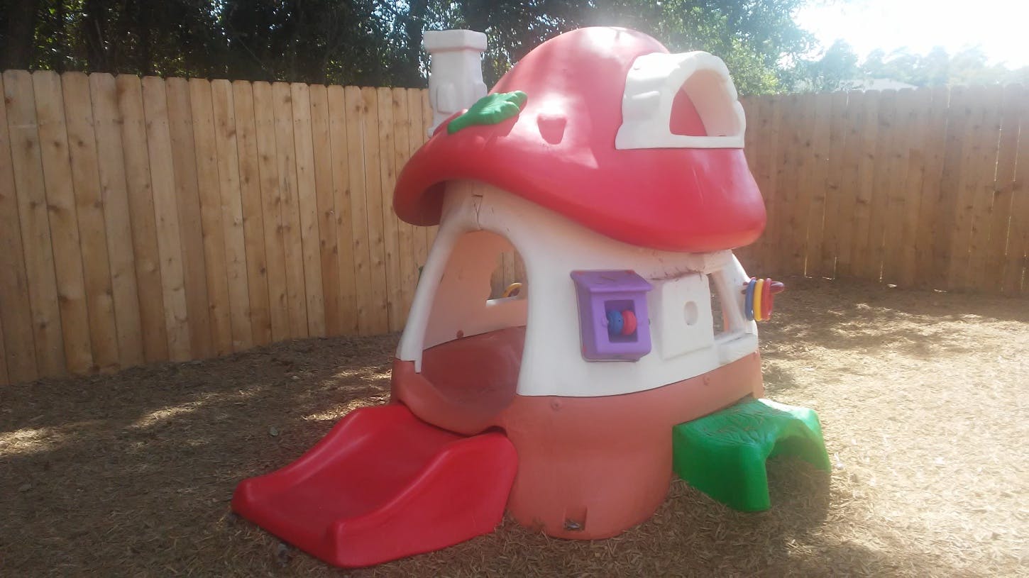 Playhouse with a red roof and a small slide