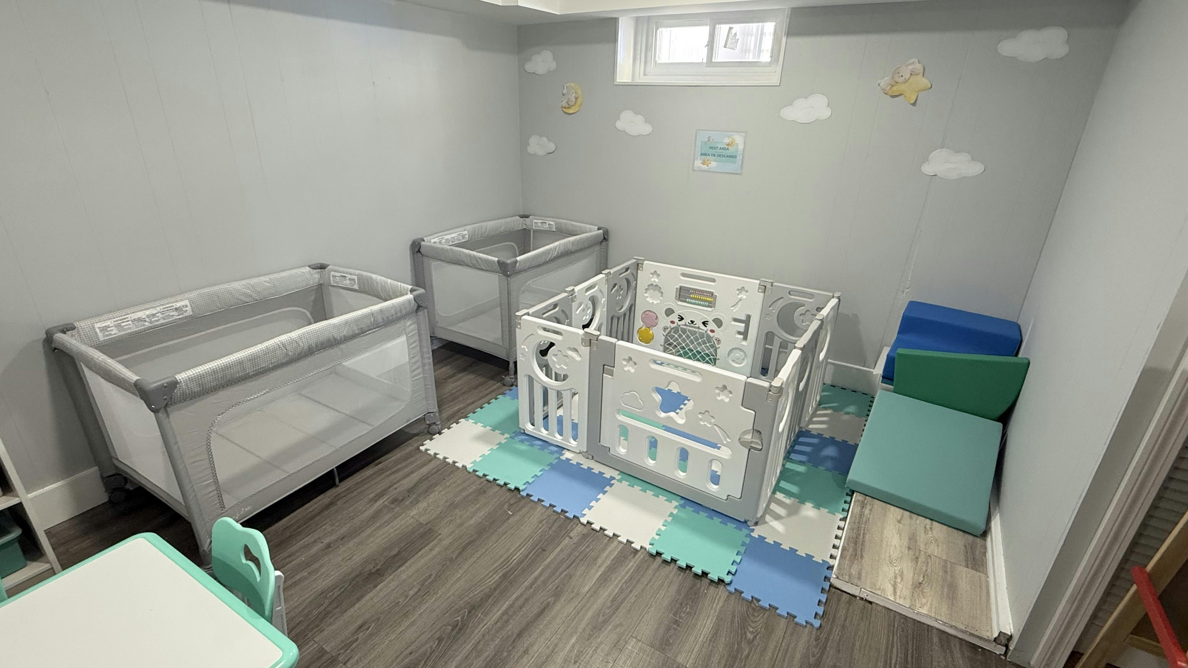 Two portable cribs and a playpen in a room with cloud decals