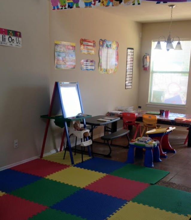 Classroom with colorful floor mats, an easel, and small tables